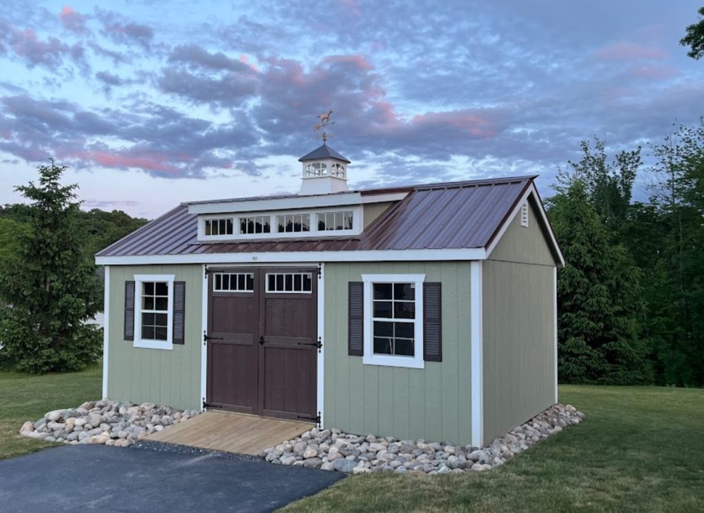 A green Smartside shed with brown doors in a yard.