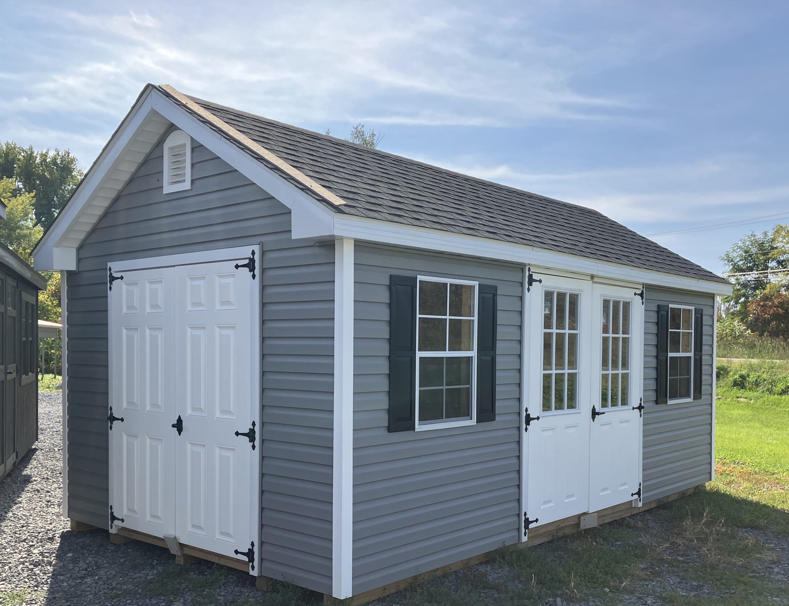 A gray shed with white doors.